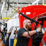 Worker assembling vehicles in a factory line.
