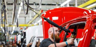 Worker assembling vehicles in a factory line.