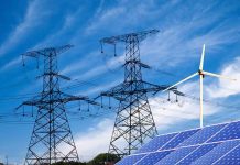 America’s Power Grid Stops Making The News Power lines, solar panels, and wind turbine against sky.