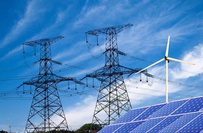 Power lines, solar panels, and wind turbine against sky.