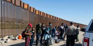 Border patrol agents interact with a group of people.