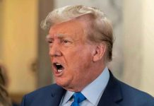 Man in suit with open mouth, speaking passionately.