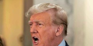 Man in suit with open mouth, speaking passionately.