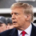 ICE Plans Massive Crackdown on Somali Community Man in suit and red tie speaking outside.