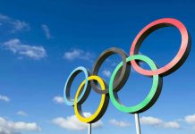 Olympic Hero Turned MOST WANTED Drug Lord Olympic rings sculpture against blue sky.