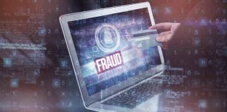 Person holding credit card near laptop displaying Fraud.
