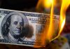 Welfare Program Breaks at Scale Burning hundred-dollar bill with visible flames.