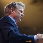 A man in a suit speaking at a podium during a conference