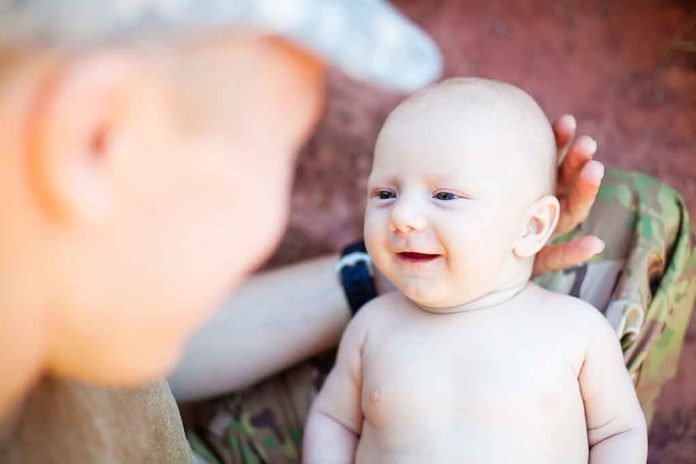 A smiling baby interacting with a parent in a military uniform