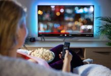 Netflix’s LGBTQ Agenda: 41% of Kids’ Shows! Person sitting on a couch watching a movie on a TV with popcorn in hand