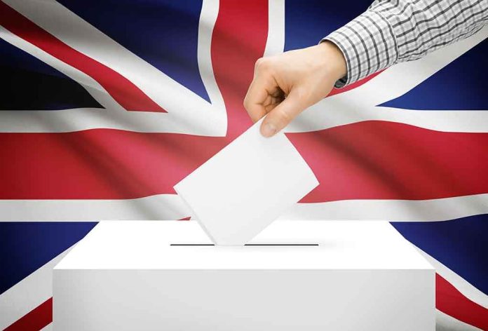 shutterstock_230787766.jpg A hand placing a ballot into a white ballot box with the British flag in the background
