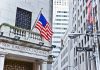 Facade of the New York Stock Exchange with an American flag and Wall Street sign