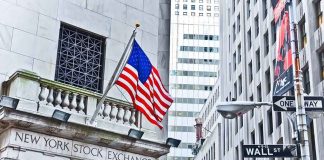 Facade of the New York Stock Exchange with an American flag and Wall Street sign