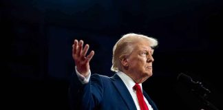 A man in a suit gesturing during a speech