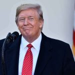Man in suit and tie speaking at podium.