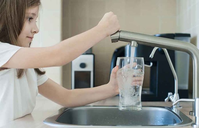 1742845301 Girl filling glass with water from kitchen faucet.