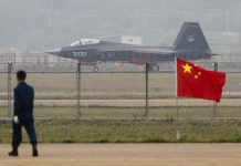 Jet with 31001 marking behind barbed wire fence.