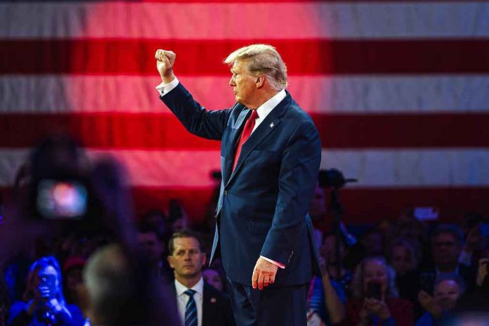 2430067439 Person in suit with fist raised in front of flag.