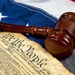 Bombshell Constitutional Warning By Supreme Court Gavel and U.S. Constitution on American flag background.