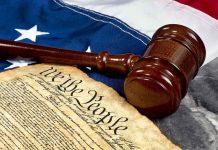 Gavel and U.S. Constitution on American flag background.