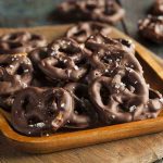 A wooden bowl filled with chocolate-covered pretzels sprinkled with sea salt