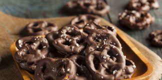 A wooden bowl filled with chocolate-covered pretzels sprinkled with sea salt