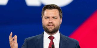 Man in a suit speaking at an event.