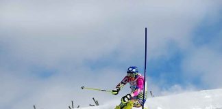 Athlete skiing down a snowy slope around a slalom pole