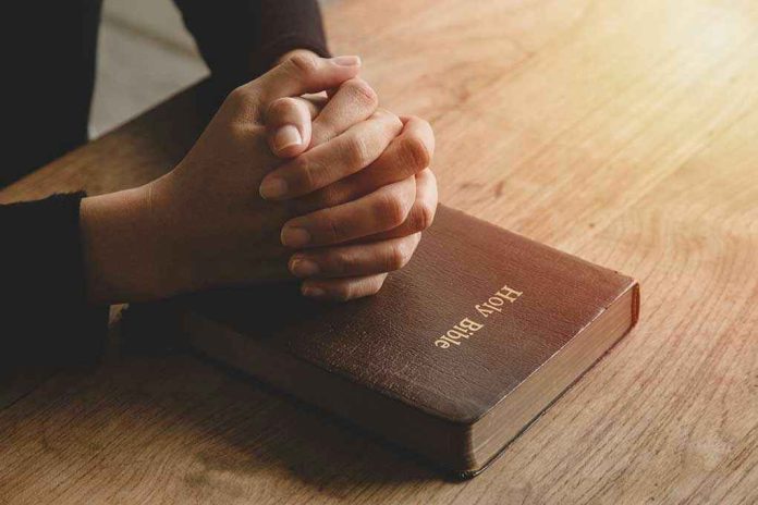 1801756960 Hands praying on a Bible.