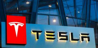 Tesla Wheels FALLING OFF—Safety Nightmare! Tesla logo on a building at night.