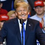 Rick Perry’s SHOCKING Trump Warning Man in suit speaking at rally with red hats.