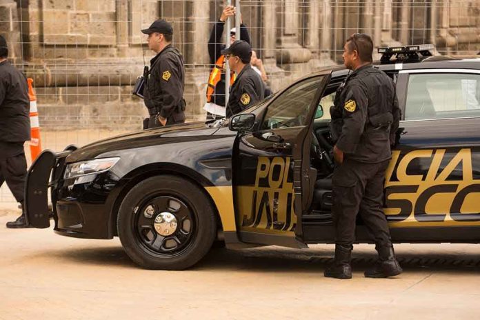 1493728583-1 Police officers standing and sitting near a patrol car.