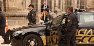 Racist Influencer Shooting: Shocking Details Missing! Police officers standing and sitting near a patrol car.
