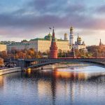 Kremlin by river at sunset with bridge.