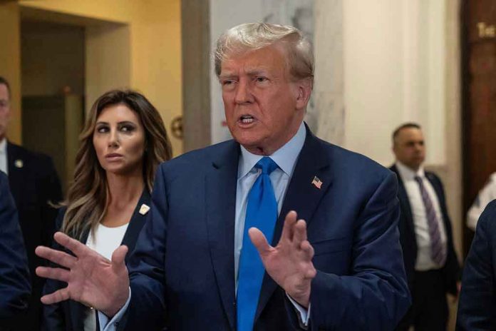 Man speaking with hands raised, woman and security behind.