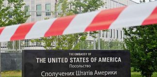 Trump Brokers Fragile Ukraine Ceasefire U.S. Embassy sign behind red-and-white caution tape.