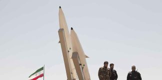 Iran’s War Warning: US Plot Revealed? Military personnel beside missiles and Iranian flag.