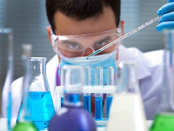 shutterstock_125266409 Scientist conducting an experiment with blue liquids in a laboratory