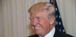 Trump’s $10B IRS Lawsuit Vanishes–Why Now? A smiling man in formal attire with an American flag in the background