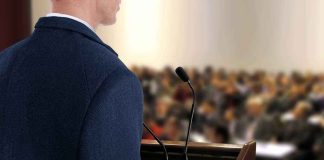 A speaker at a podium addressing an audience