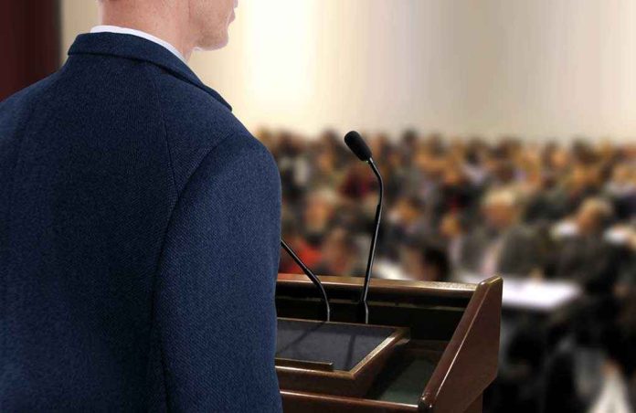 shutterstock_200679422 A speaker at a podium addressing an audience