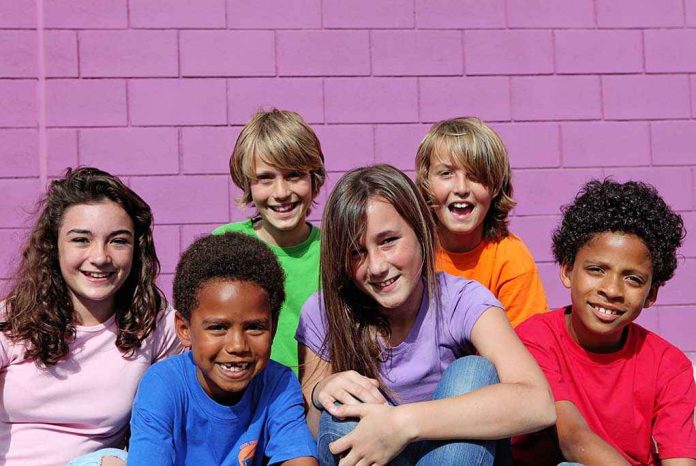 shutterstock_40854085 A group of six children smiling together in front of a purple wall