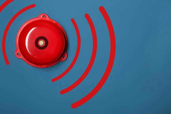 1311134939-1 Red alarm bell on a blue background.