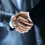 Streaming Shake-Up — How The NEW MERGER AFFECTS YOU Two individuals in suits shaking hands firmly.