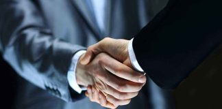 Streaming Shake-Up — How The NEW MERGER AFFECTS YOU Two individuals in suits shaking hands firmly.