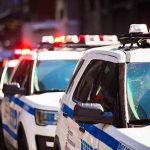 Police cars with flashing lights in line formation.