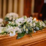PALACE Wall SEALS Princess’s Death SECRECY Flower arrangement on a wooden casket at a funeral.
