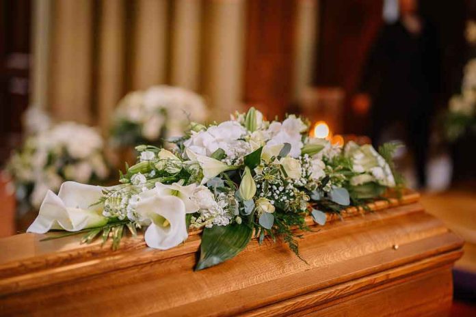 2288021055-1 Flower arrangement on a wooden casket at a funeral.