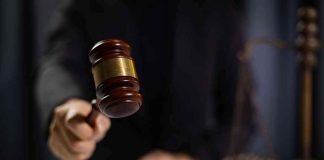 Heart-Carving HORROR — MS-13 VERDICT Stuns Hand holding gavel in courtroom setting.