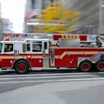 TOXIC PLUME Chokes The CITY— EVEN MORE Foul Issues EXPOSED Red fire truck driving through city street crosswalk